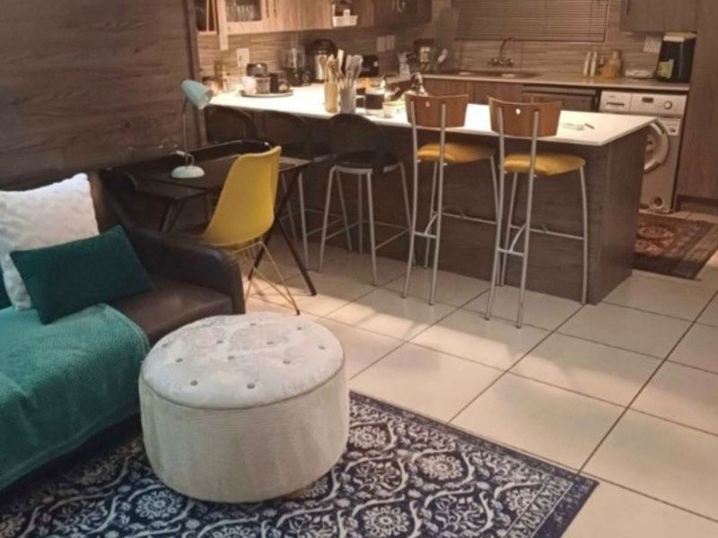 Open-plan living and kitchen area featuring modern cabinetry, a breakfast island, tiled flooring, and integrated laundry plumbing.