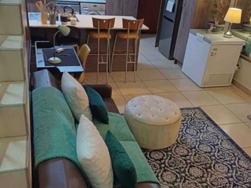 Open-plan living area featuring a kitchen with built-in cabinetry, a central island, and tiled flooring, seamlessly connected to the lounge space.