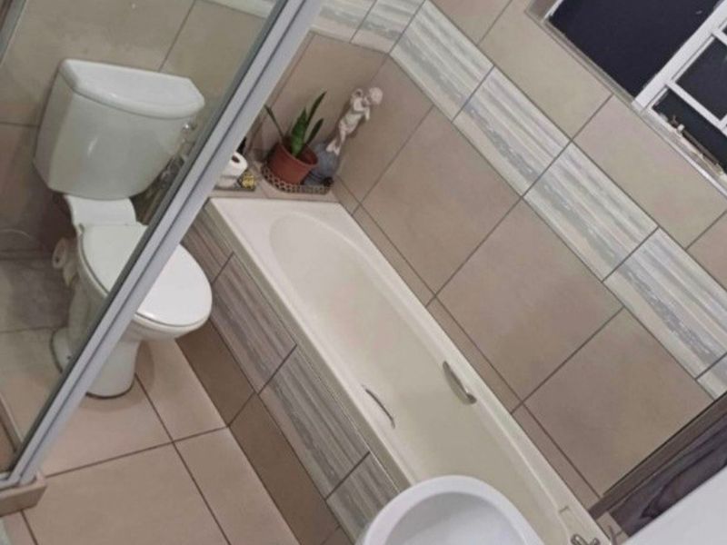 A functional bathroom featuring a built-in bathtub, pedestal basin, toilet, and a separate shower enclosure with tiled finishes throughout.