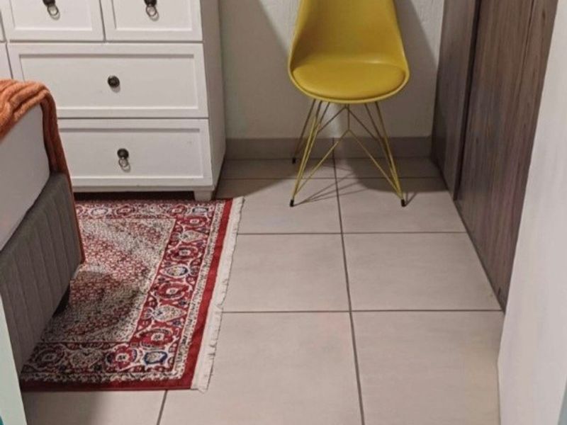A bedroom interior featuring neutral tiled flooring and built-in wooden cupboards.