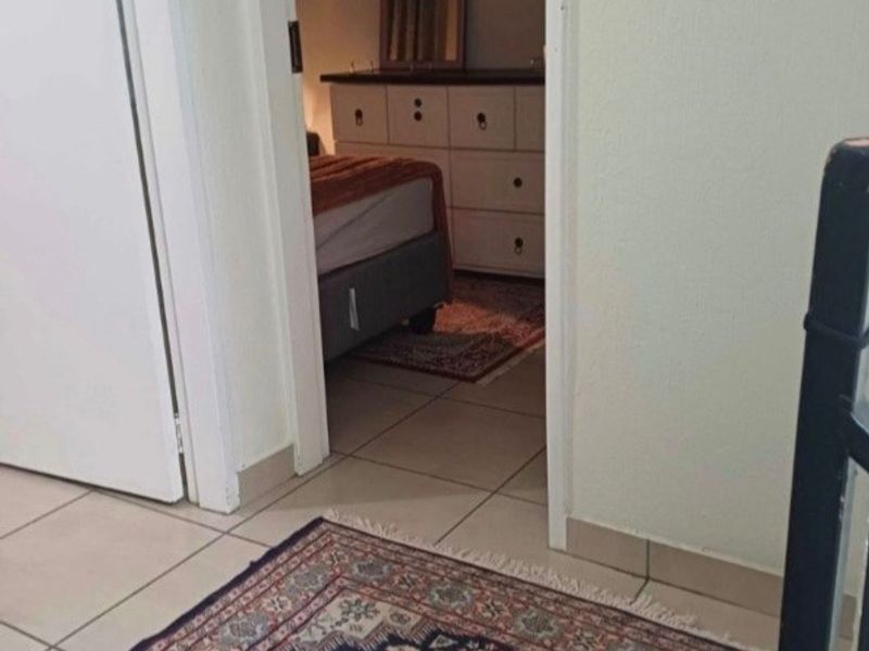 A view from a tiled hallway looking into an adjacent bedroom space.