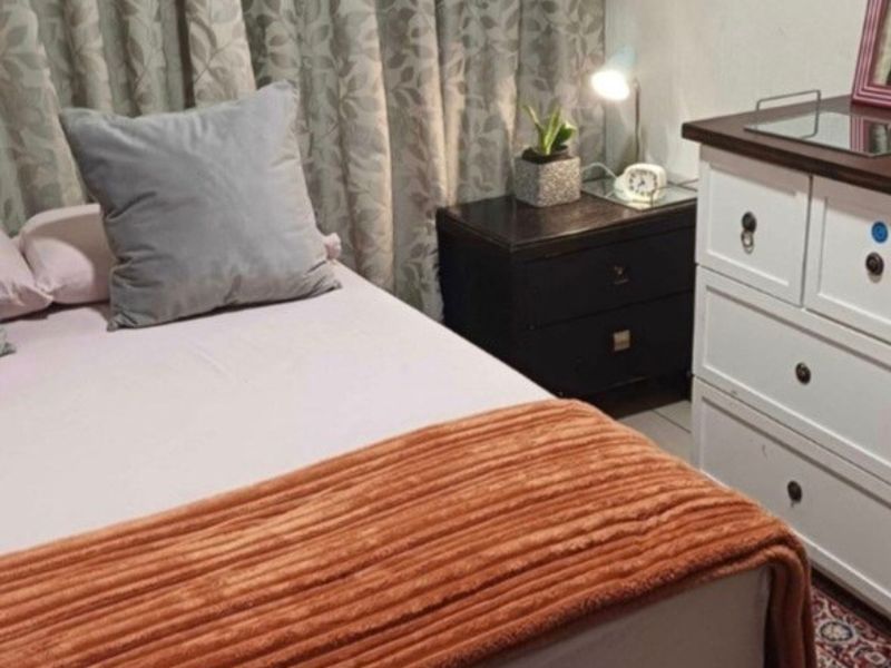 A bedroom featuring neutral wall finishes and window curtains.