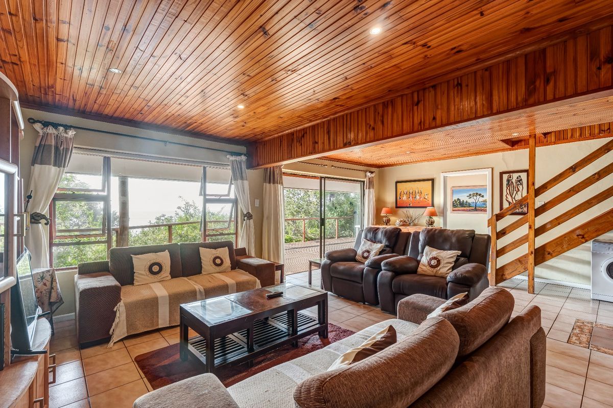 Spacious living area featuring a warm timber-clad ceiling, tiled flooring, and large sliding doors that provide natural light and access to the outdoor space.
