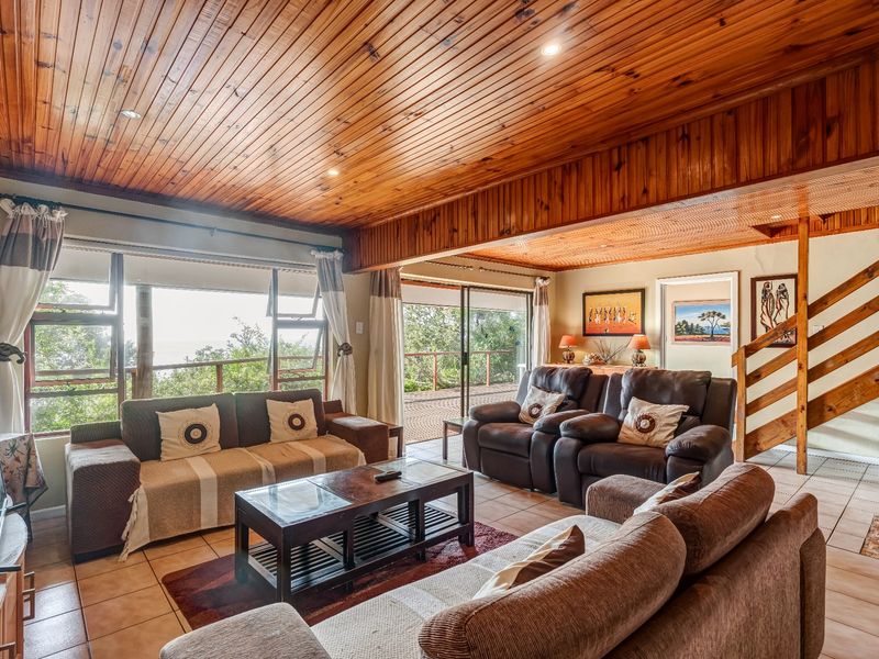 Spacious living area featuring a warm timber-clad ceiling, tiled flooring, and large sliding doors that provide natural light and access to the outdoor space.