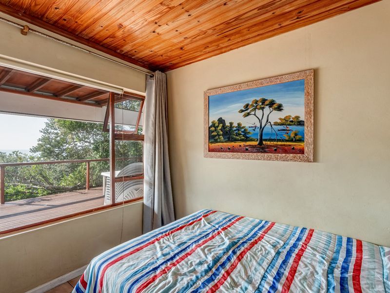 A bedroom featuring a warm timber tongue and groove ceiling and direct access to an outdoor balcony through a large window and door.