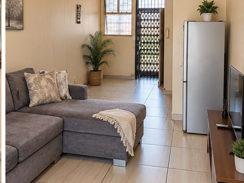 A living area featuring neutral tiled flooring, a ceiling fan, and a secure entrance with a metal security gate.