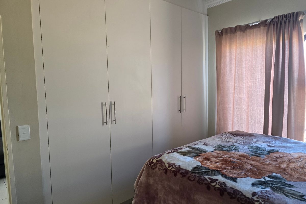 A bedroom featuring floor-to-ceiling built-in cupboards with modern handles and decorative ceiling cornice.