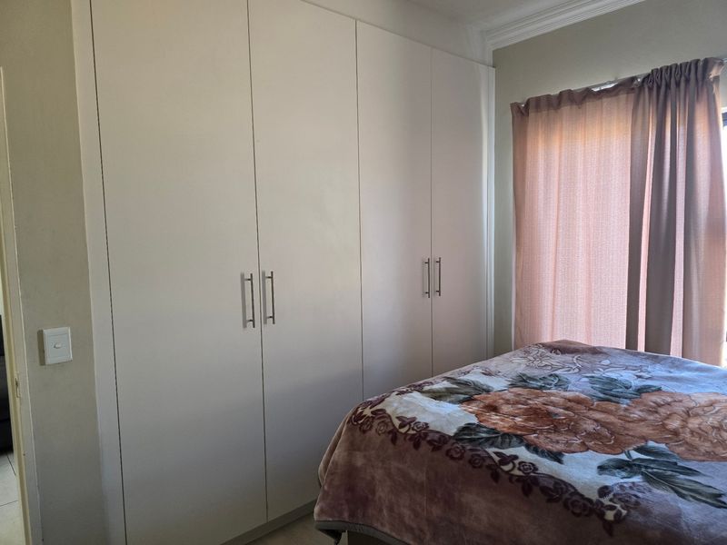 A bedroom featuring floor-to-ceiling built-in cupboards with modern handles and decorative ceiling cornice.