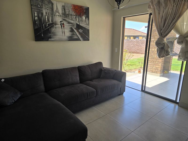 A bright living room featuring large format floor tiles and a sliding glass door providing direct access to an outdoor patio area.