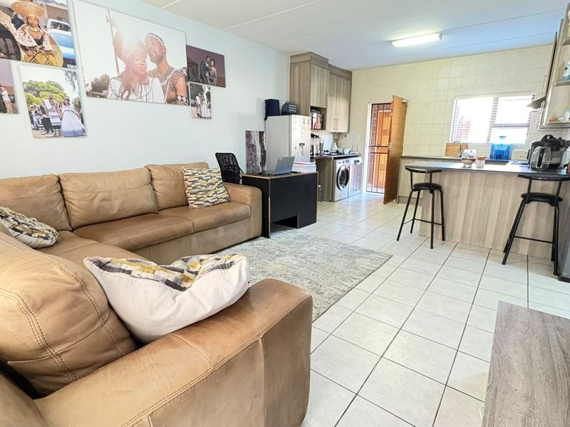 Open-plan living and kitchen area featuring tiled flooring, a breakfast bar, and functional cabinetry, providing a versatile space for daily living.