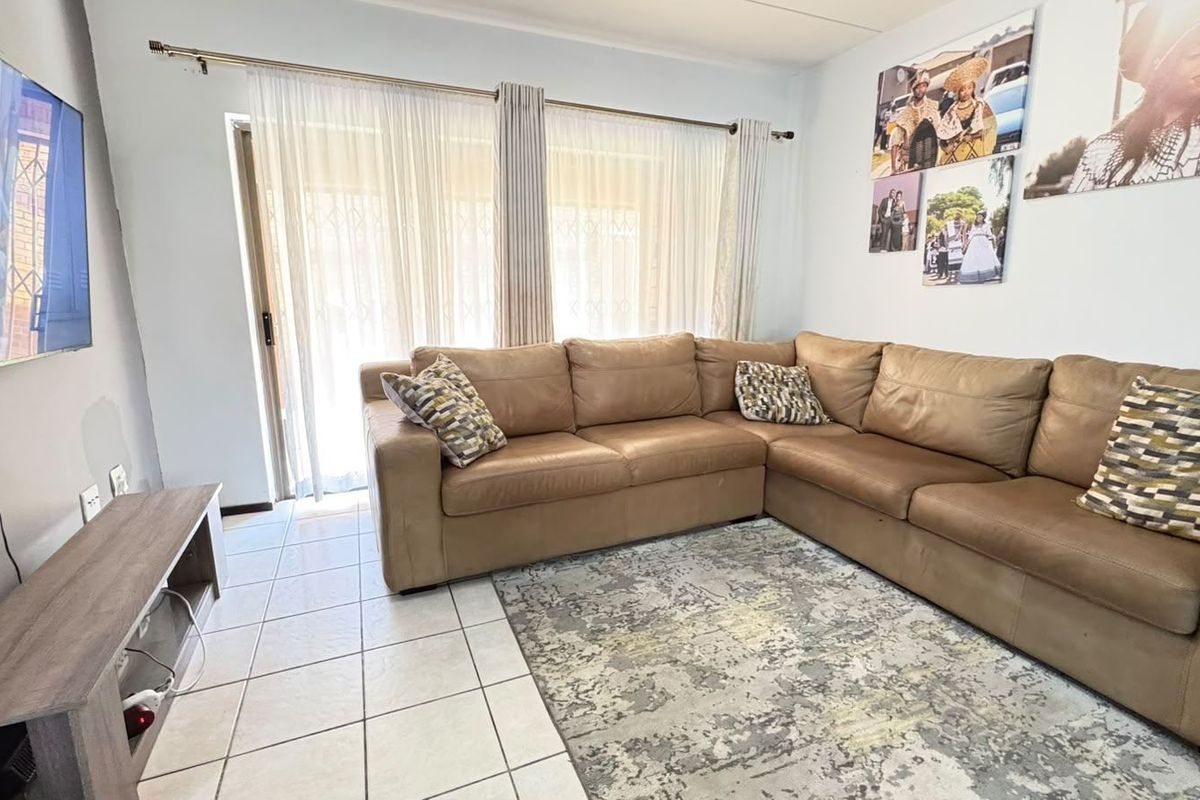 A bright living room featuring tiled flooring and a large sliding glass door that provides natural light and access to the exterior.