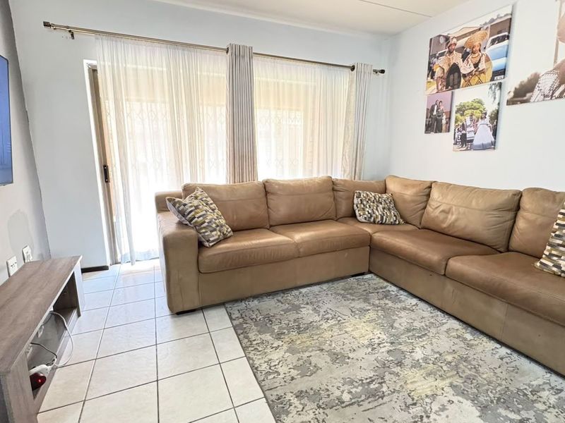 A bright living room featuring tiled flooring and a large sliding glass door that provides natural light and access to the exterior.
