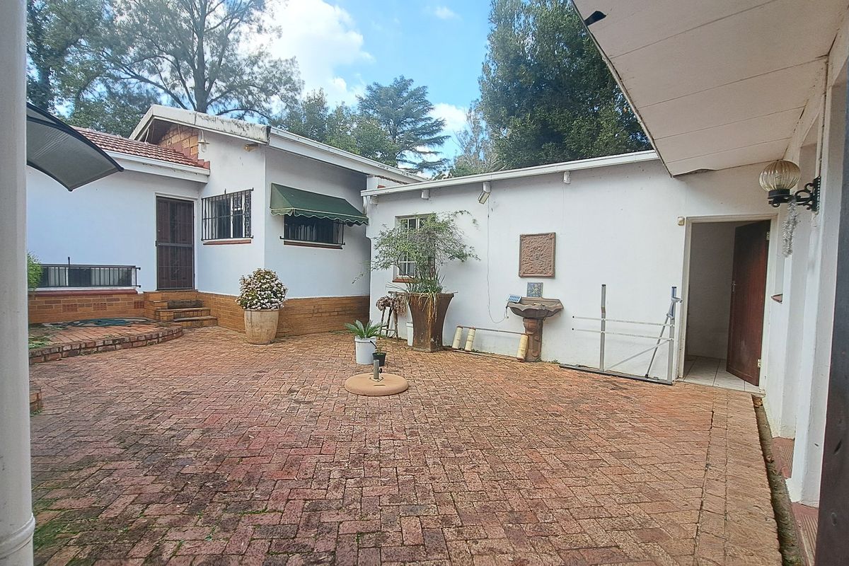 A paved rear courtyard area featuring brick surfaces, security bars on windows, and an external wall-mounted basin, offering potential for outdoor entertainment space.