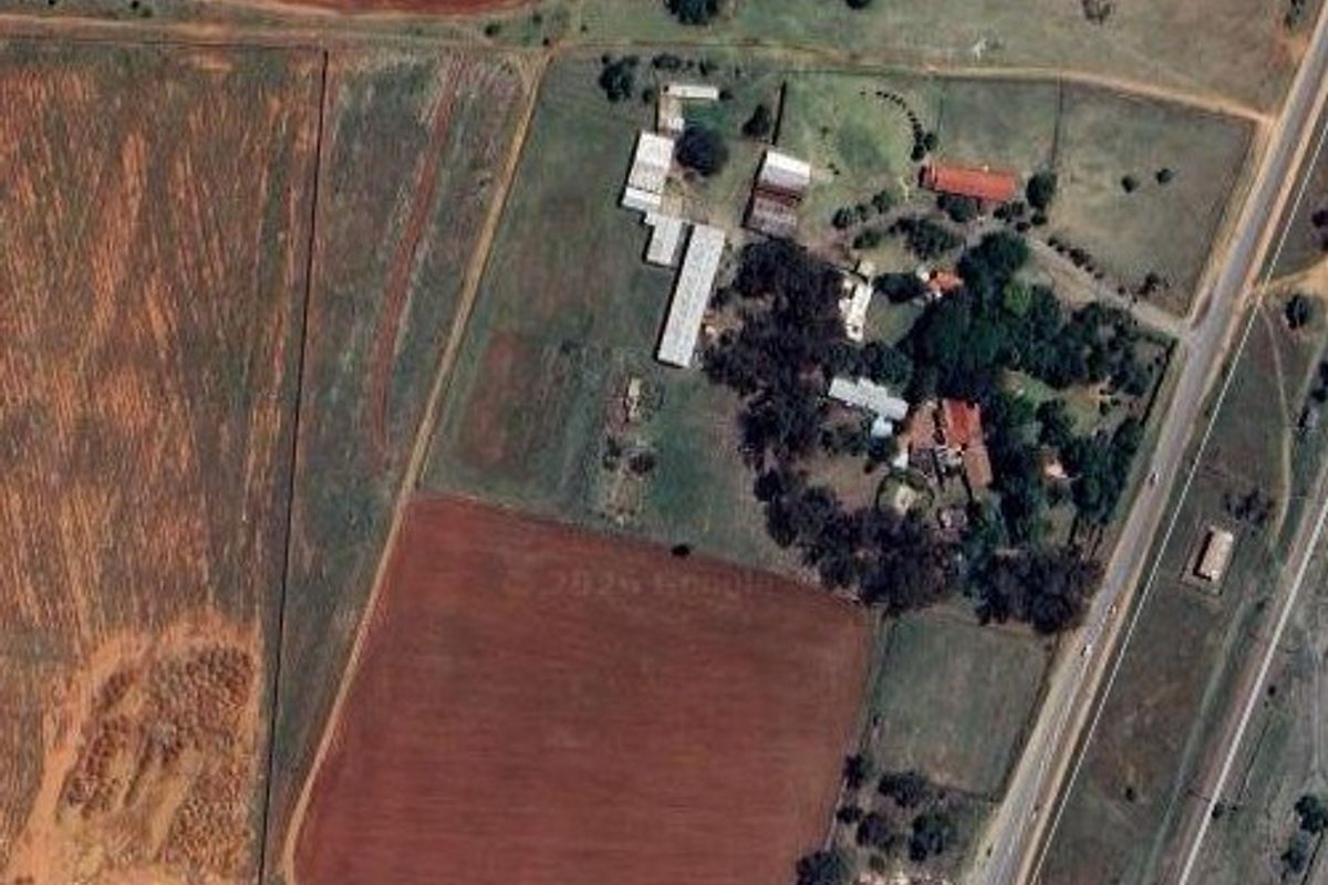 Aerial view of a large commercial property featuring multiple outbuildings, main structures, and extensive surrounding land with road access.