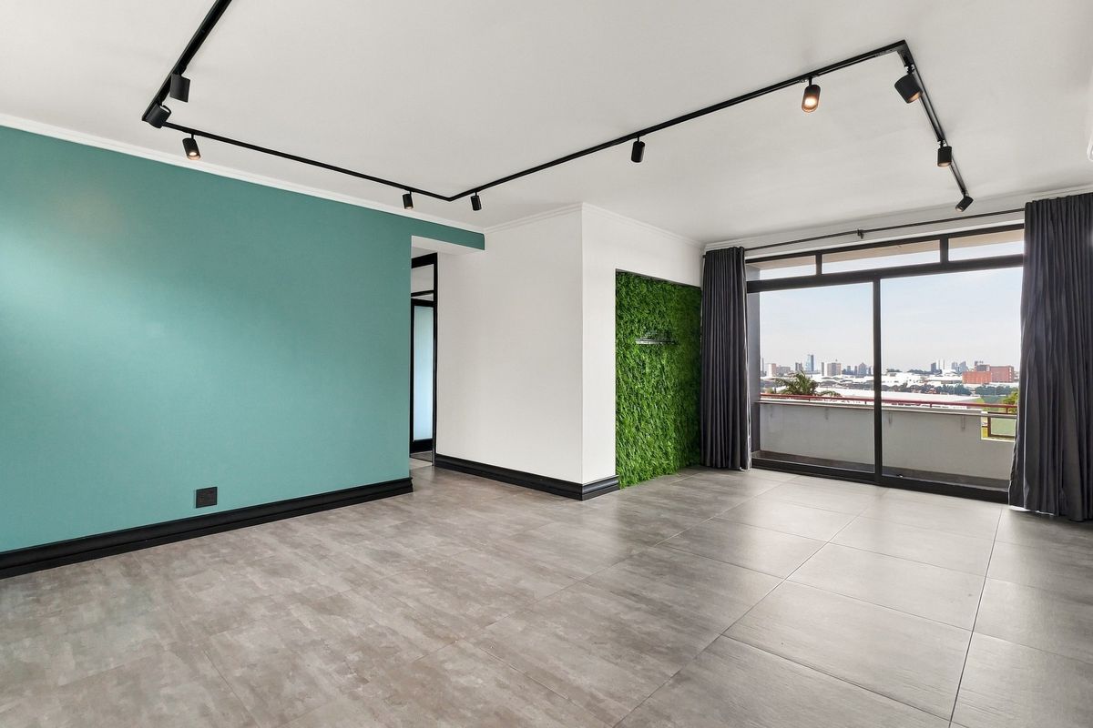 Spacious living area featuring modern track lighting, large format floor tiles, and direct access to a balcony with city views.