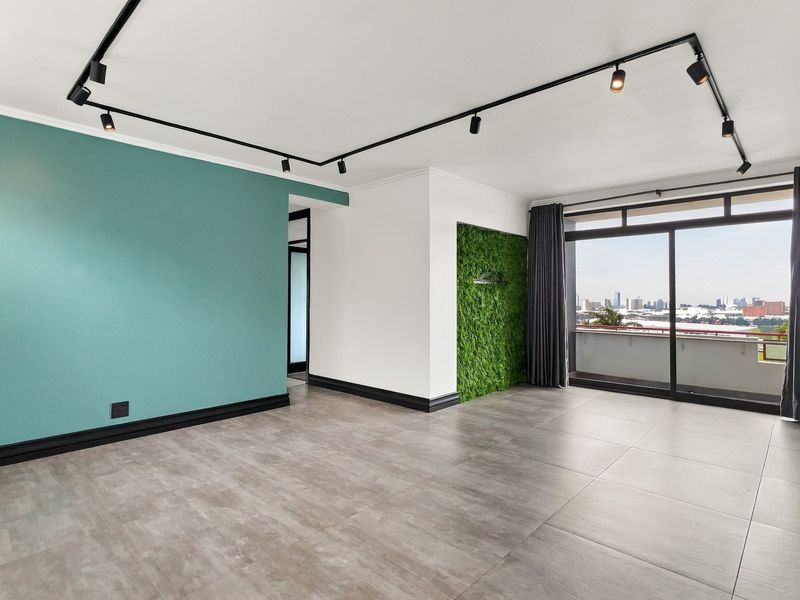 Spacious living area featuring modern track lighting, large format floor tiles, and direct access to a balcony with city views.