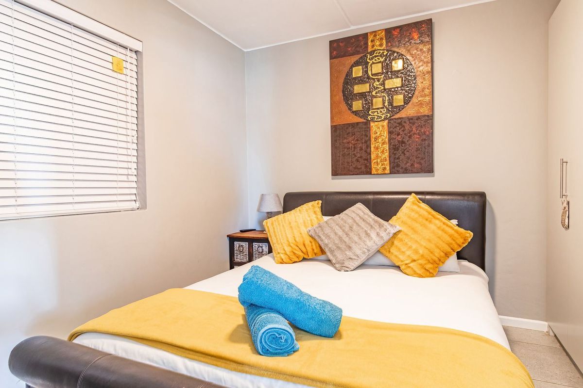 A well-maintained bedroom featuring neutral wall tones, a built-in wardrobe for storage, and venetian blinds for light control.