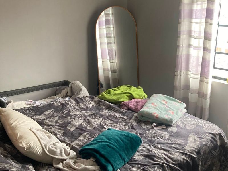 A bedroom featuring a window with a curtain rod, providing natural light to the space.