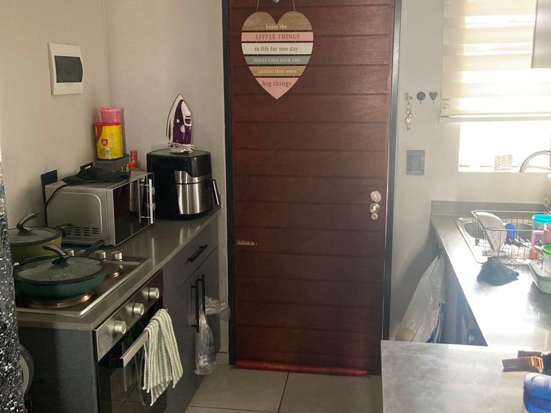 A functional kitchen featuring built-in cabinetry, a stainless steel sink, a built-in oven with hob, and tiled flooring.