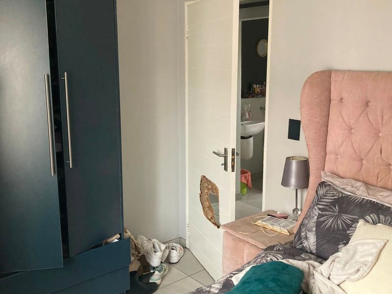Bedroom featuring a built-in wardrobe and an internal door with visible structural damage to the panel.