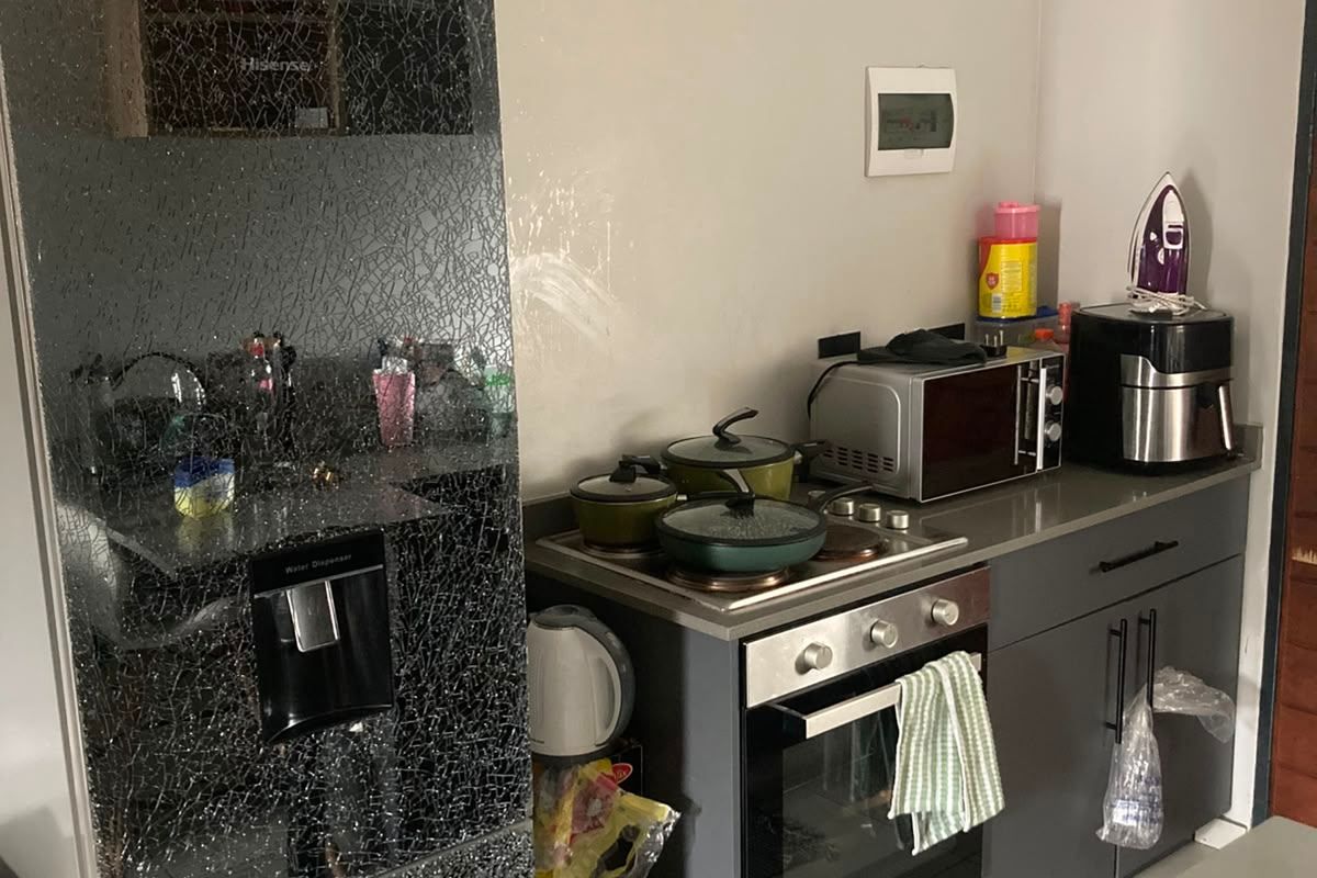 Compact kitchen featuring modern grey cabinetry, built-in oven, electric hob, and stone countertops, finished with neutral wall paint and tiled flooring.