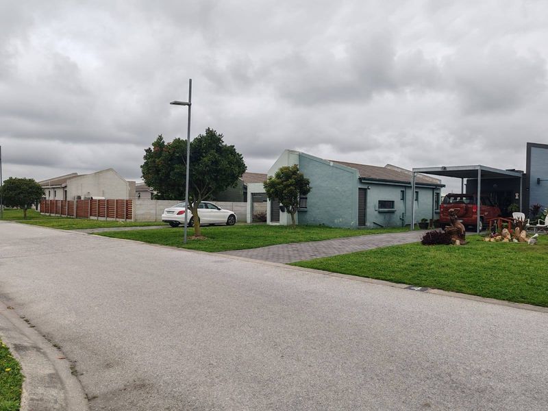 Street view of a townhouse complex featuring a paved driveway, carport, and landscaped front lawn area.