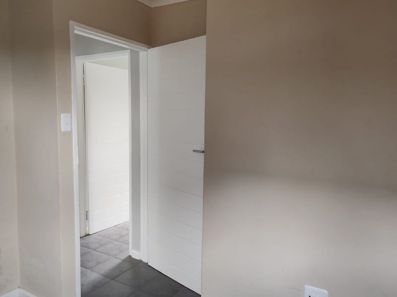 A neutral-toned hallway featuring tiled flooring and white internal doors, providing access to adjacent rooms within the townhouse.