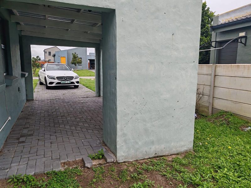 A covered carport area featuring a paved driveway and concrete structural pillars, providing sheltered parking space for the property.