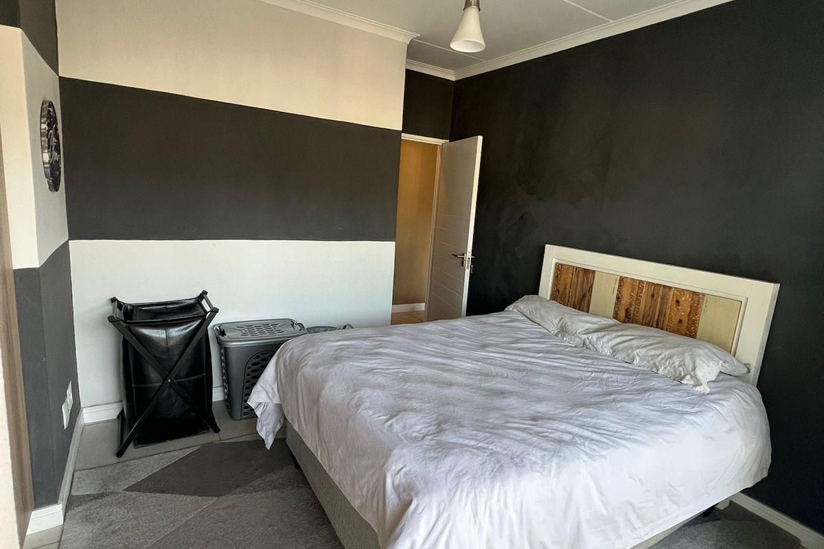 A bedroom featuring tiled flooring, coved ceilings, and a modern pendant light fixture with a bold two-tone wall paint scheme.