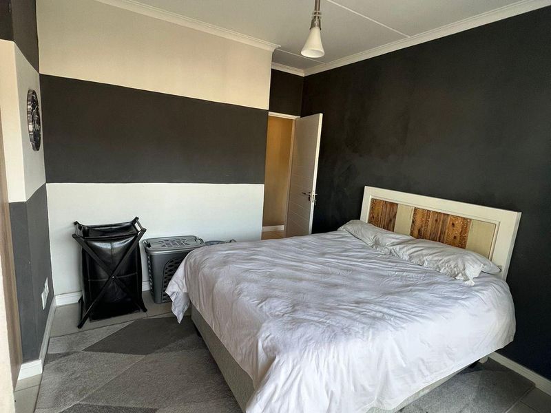 A bedroom featuring tiled flooring, coved ceilings, and a modern pendant light fixture with a bold two-tone wall paint scheme.