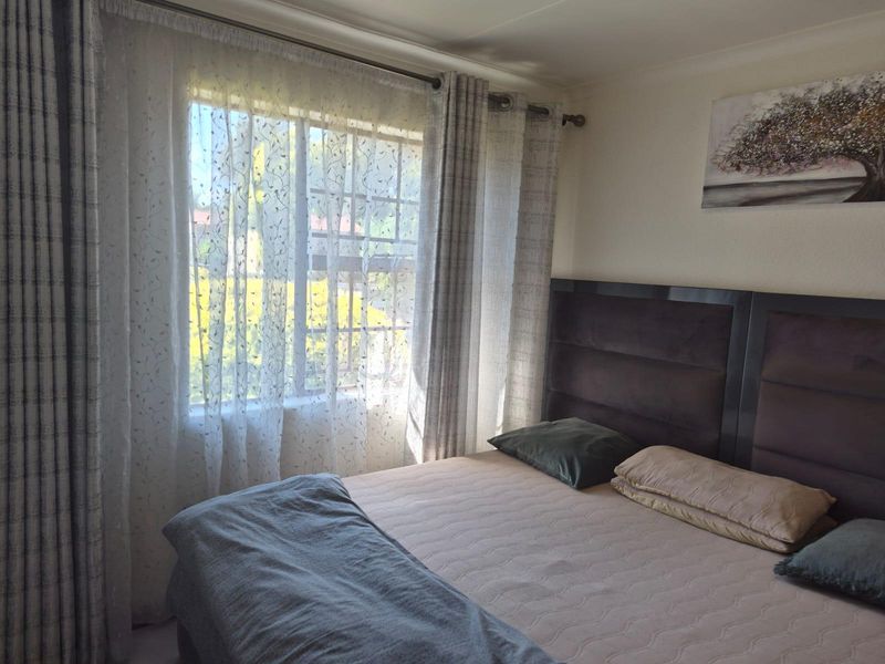 A well-lit bedroom featuring a large window with installed curtain rails, providing natural light and a view of the exterior.