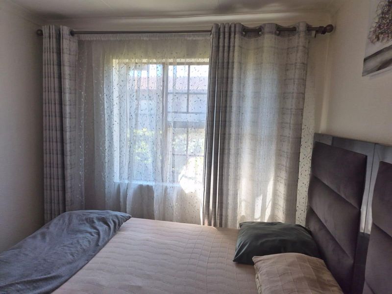 A bedroom featuring a window with a curtain rod and curtains.