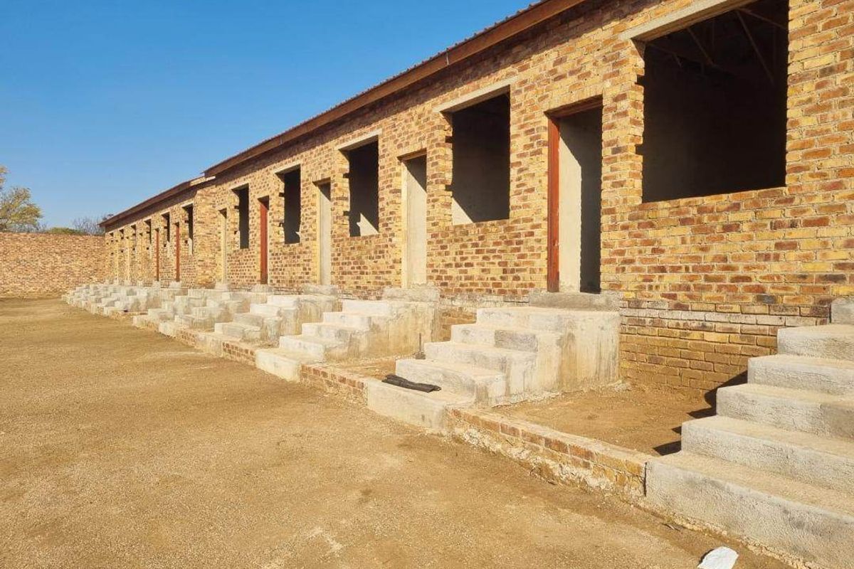 A row of unfinished apartment units featuring exposed brickwork and concrete staircases, currently in the early stages of construction.