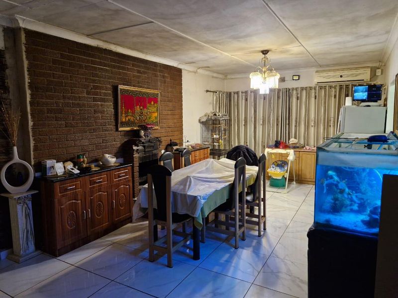 Dining room featuring an exposed brick feature wall, tiled flooring, and built-in cabinetry, offering a functional space with potential for cosmetic updates.