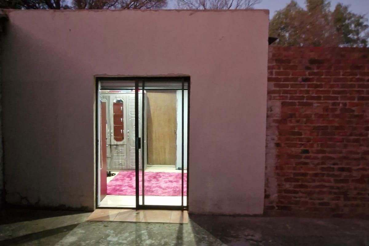 Rear view of the property showing a sliding glass door entrance, concrete patio area, and exposed brick wall section at dusk.