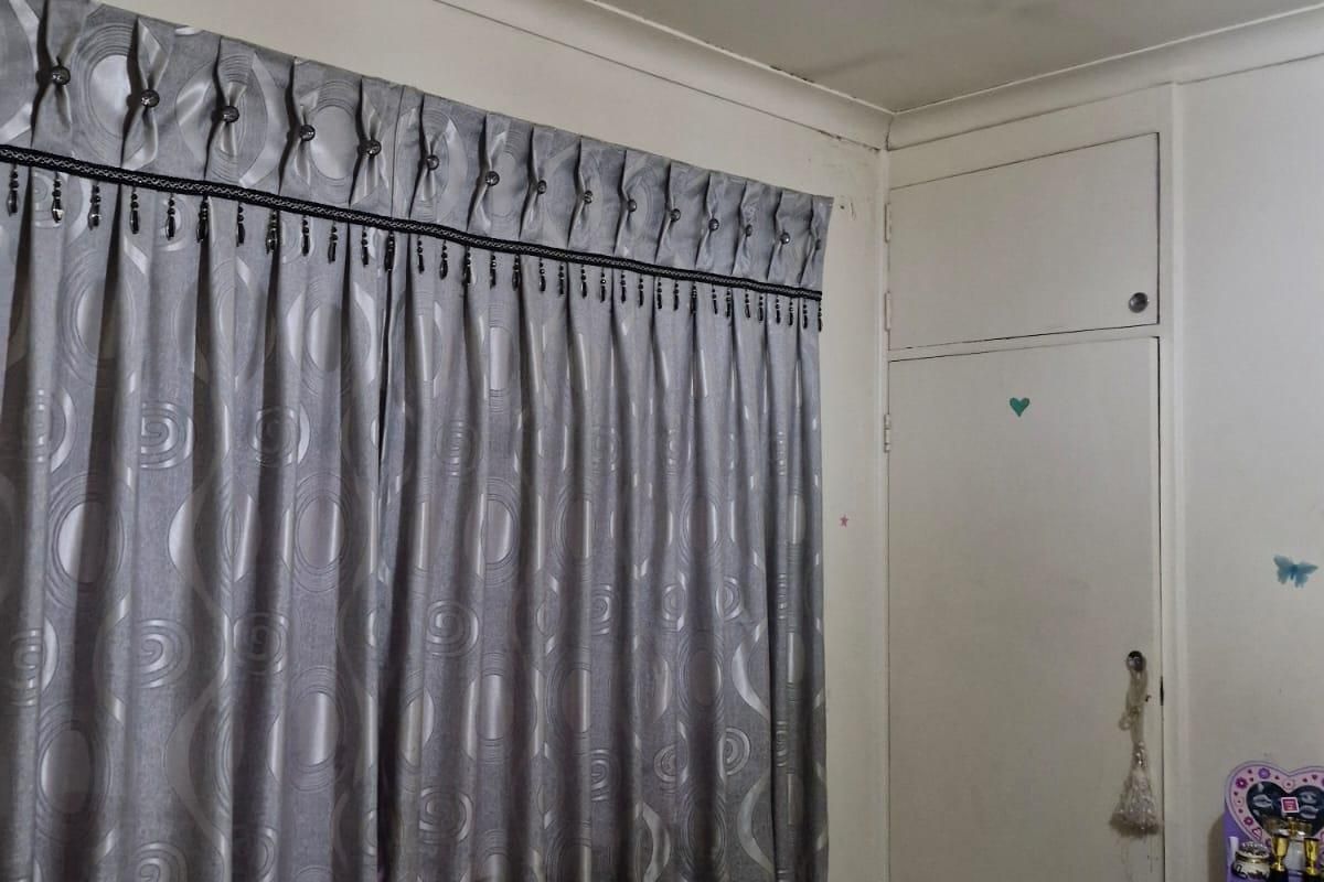 A bedroom featuring a built-in cupboard and coved ceiling, showing signs of ceiling staining.