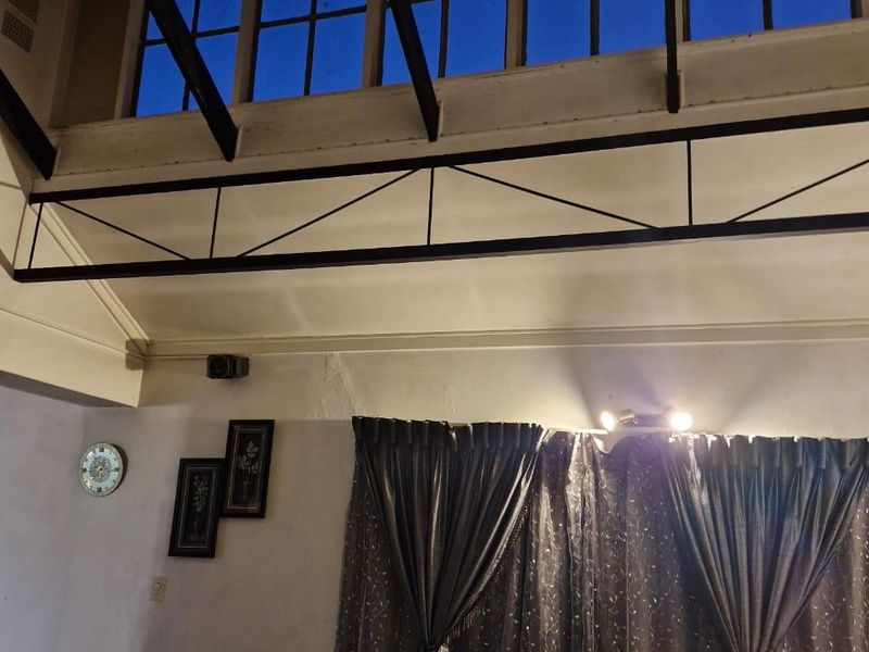 Living room featuring high vaulted ceilings with exposed timber rafters, a decorative steel truss, and clerestory windows providing natural light.