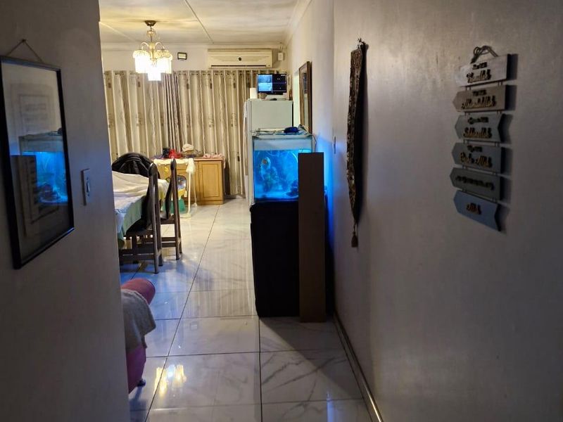 Open-plan living area featuring tiled flooring and a wall-mounted air conditioning unit, showing signs of ceiling water damage.