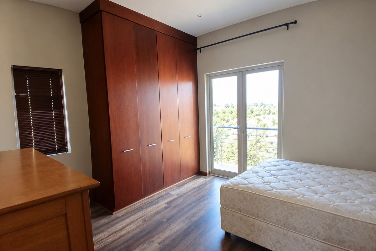 Bedroom featuring dark wood built-in cupboards, laminate flooring, and a glass door leading to a balcony with scenic views.