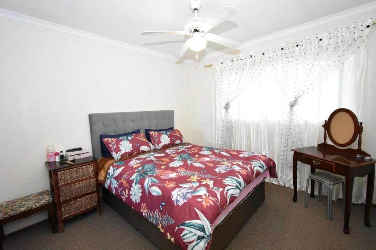A standard bedroom featuring carpeted flooring and a ceiling fan, providing a functional and comfortable living space.