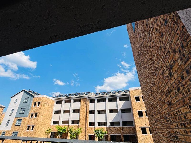 View of the apartment complex exterior featuring brick facade construction and roof-mounted solar water heating panels.