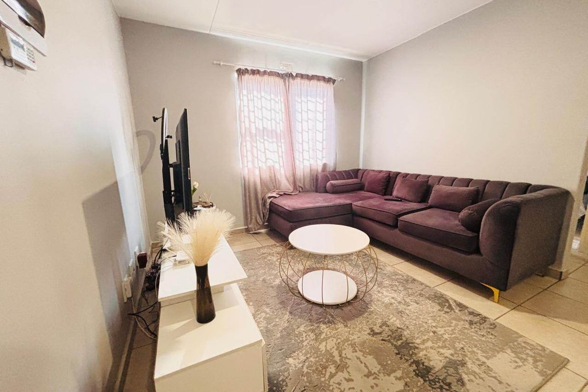 A living room featuring neutral wall tones and tiled flooring, providing a functional space for relaxation and entertainment.