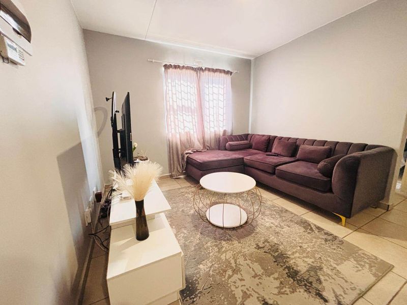 A living room featuring neutral wall tones and tiled flooring, providing a functional space for relaxation and entertainment.