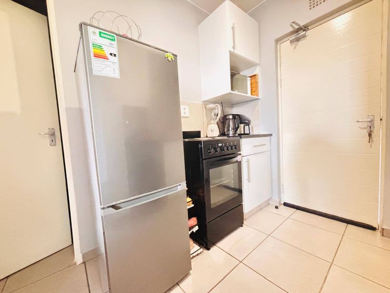 A compact kitchen area featuring built-in cabinetry, a freestanding oven and hob, and tiled flooring, providing a functional space for meal preparation.