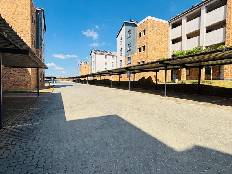 A well-maintained outdoor parking area featuring multiple covered parking bays with paved surfaces between apartment building blocks.