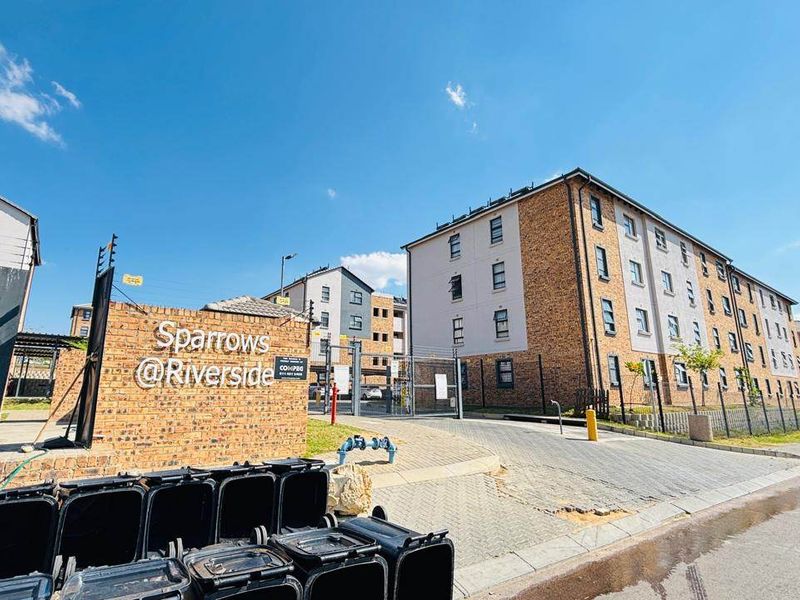 Exterior view of the Sparrows @ Riverside apartment complex, featuring brick facade buildings, secure gated entrance, and paved driveway access.