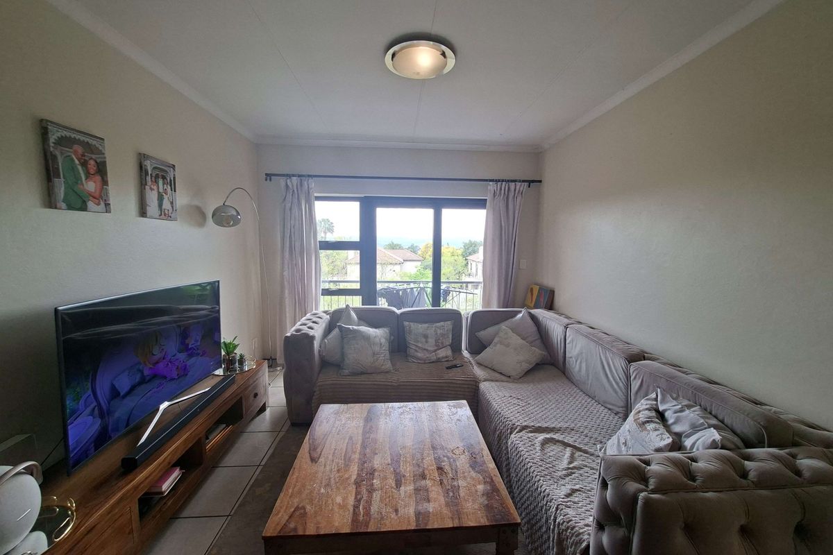 A comfortable living room featuring tiled flooring and a sliding glass door that provides natural light and access to the outdoor area.