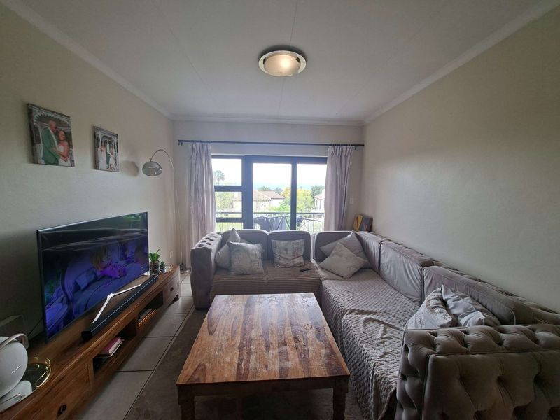 A comfortable living room featuring tiled flooring and a sliding glass door that provides natural light and access to the outdoor area.