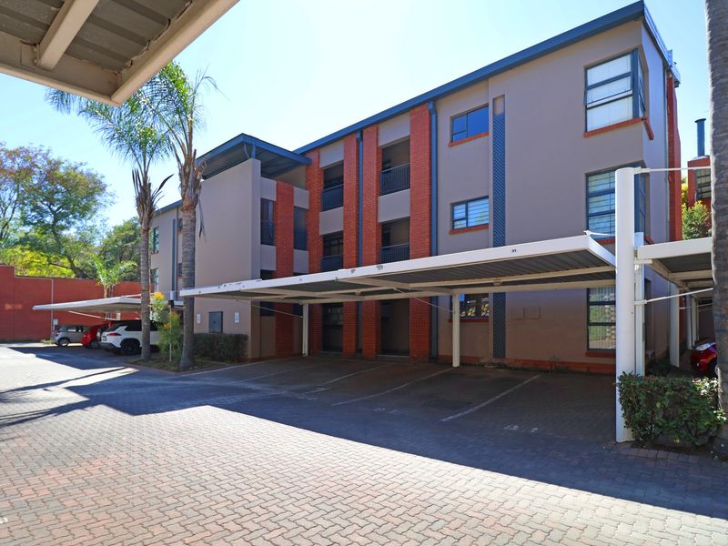 Exterior view of a multi-story townhouse complex featuring covered parking bays and brick architectural detailing.