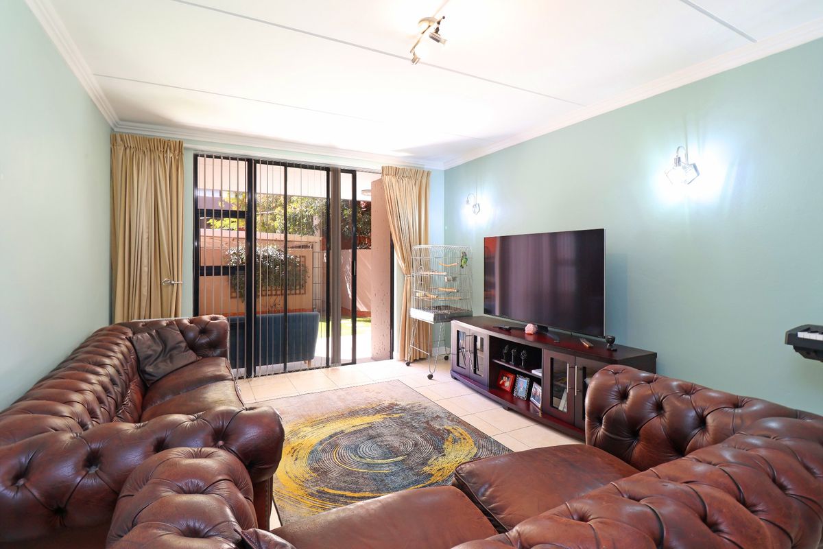 A living room featuring tiled flooring, coving, and sliding glass doors with security gates providing access to the outdoor area.